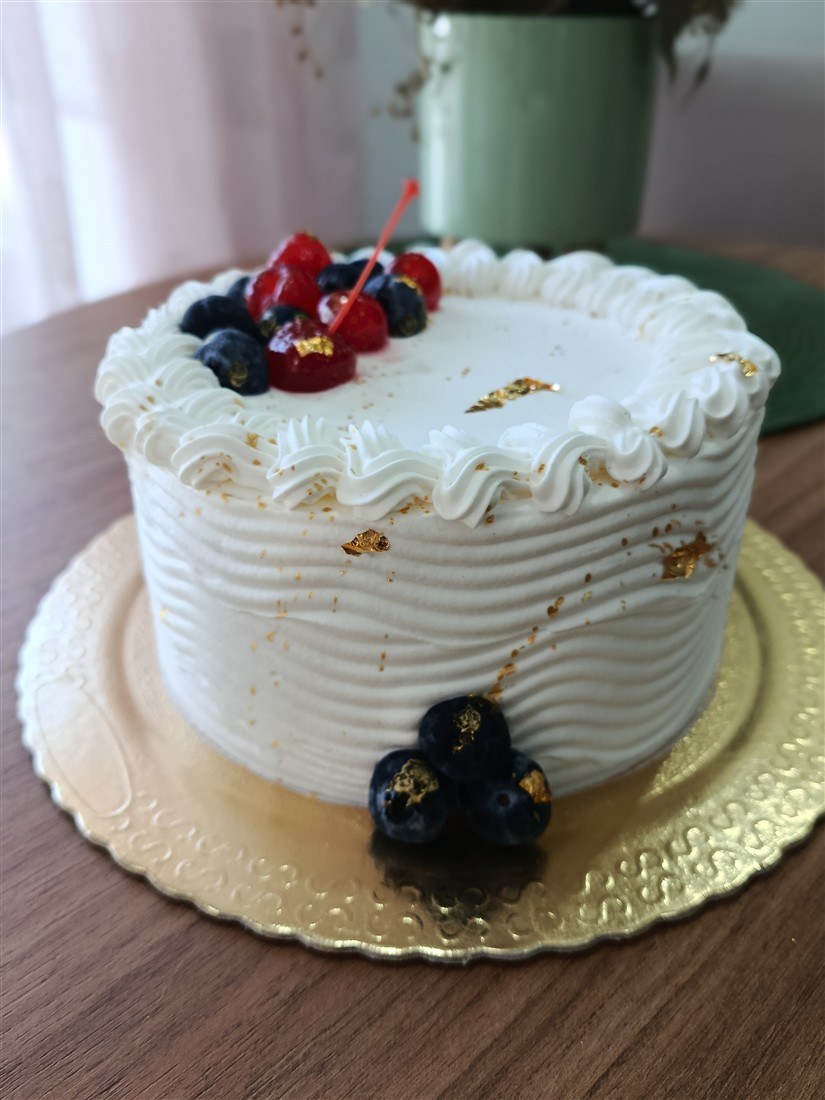Bolo branco com frutas vermelhas e detalhes dourados
