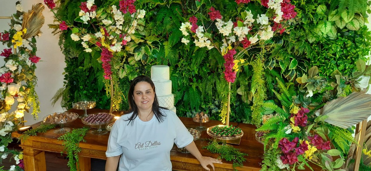 Elaine ao lado de uma mesa de doces decorada com flores