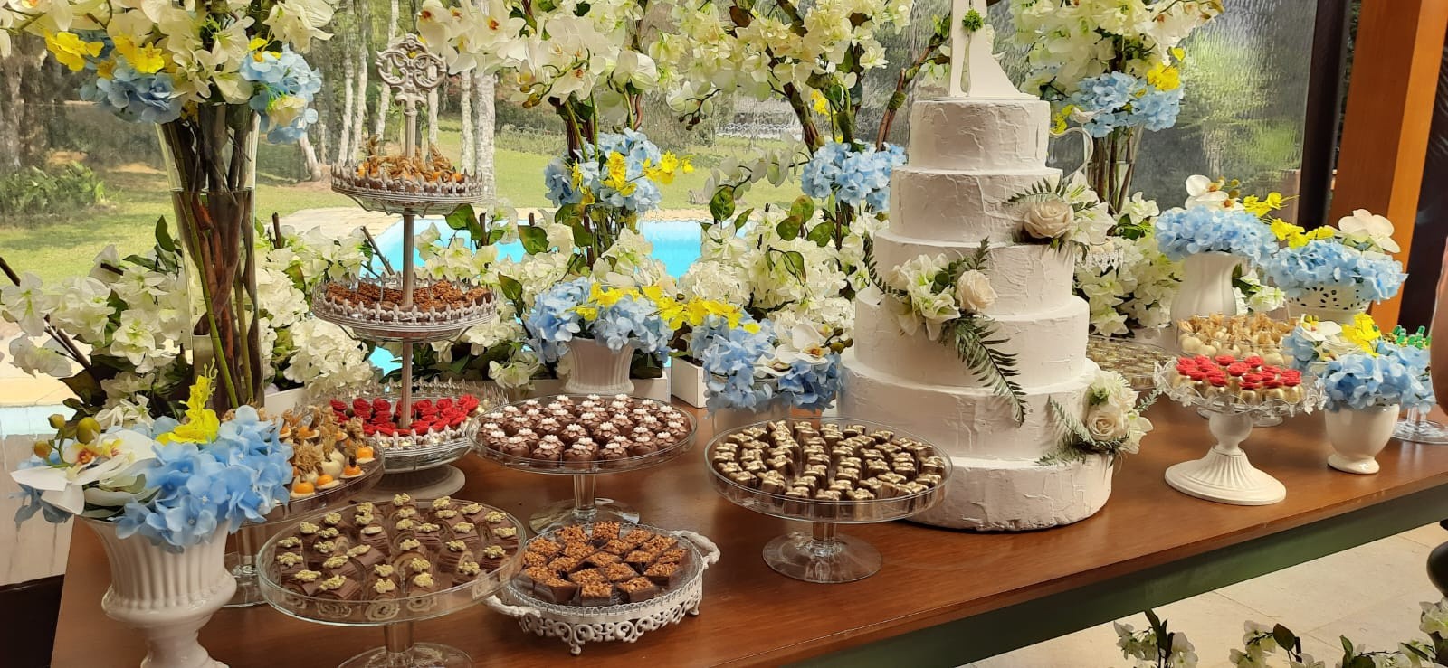 Mesa de doces e bolo de casamento decorados com flores